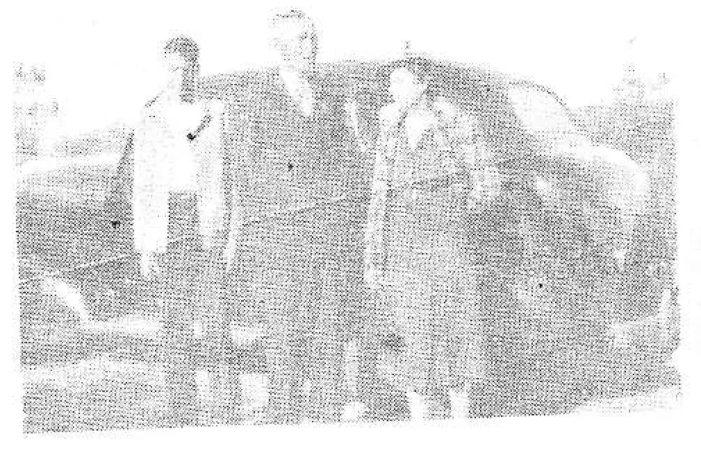 Faded/overexposed group photo of several people standing near a car