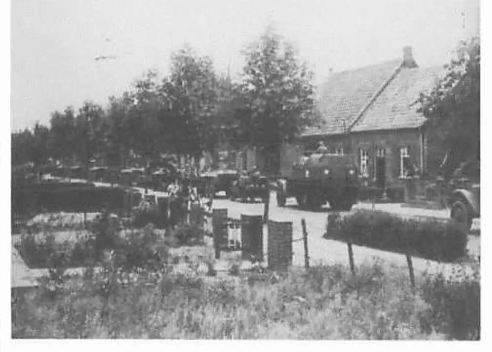Military vehicles parked along a garden/park area with hedges near a house, part of the 15th Cavalry Squadron in Maasniel.