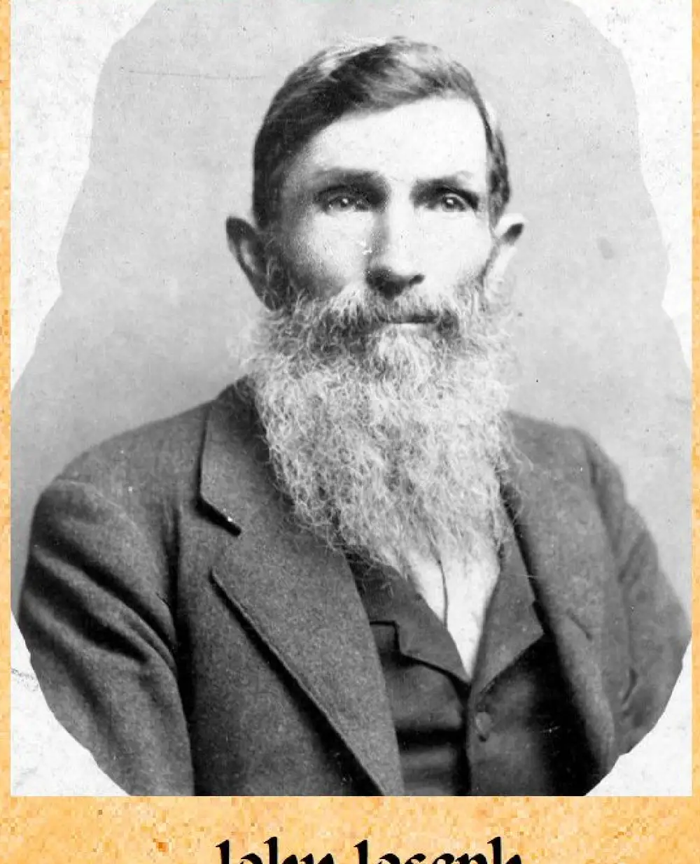 Studio portrait of an elderly man with a long white beard, wearing a suit jacket.