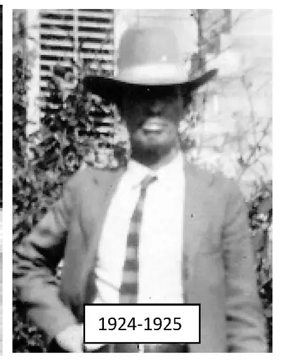 Photograph of a man in a suit and tie wearing a wide-brimmed hat, standing outdoors near a trellis with plants.